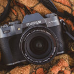 Close up photo of a Fujifilm X-T50 camera and XF16-50mm lens positioned on an orange patterned towel