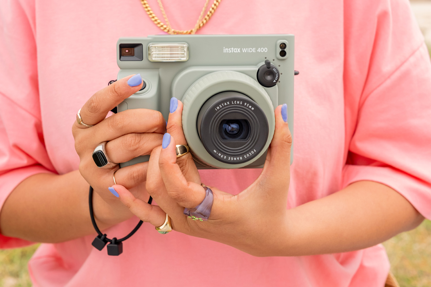 Lifestyle photo of Instax Wide 400 held by person in pink t-shirt