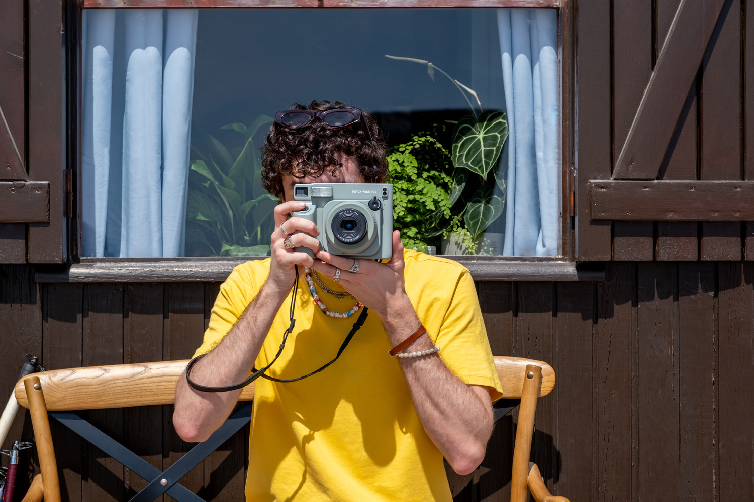 Man in yellow t-shirt holding instax wide 400 camera to his eye