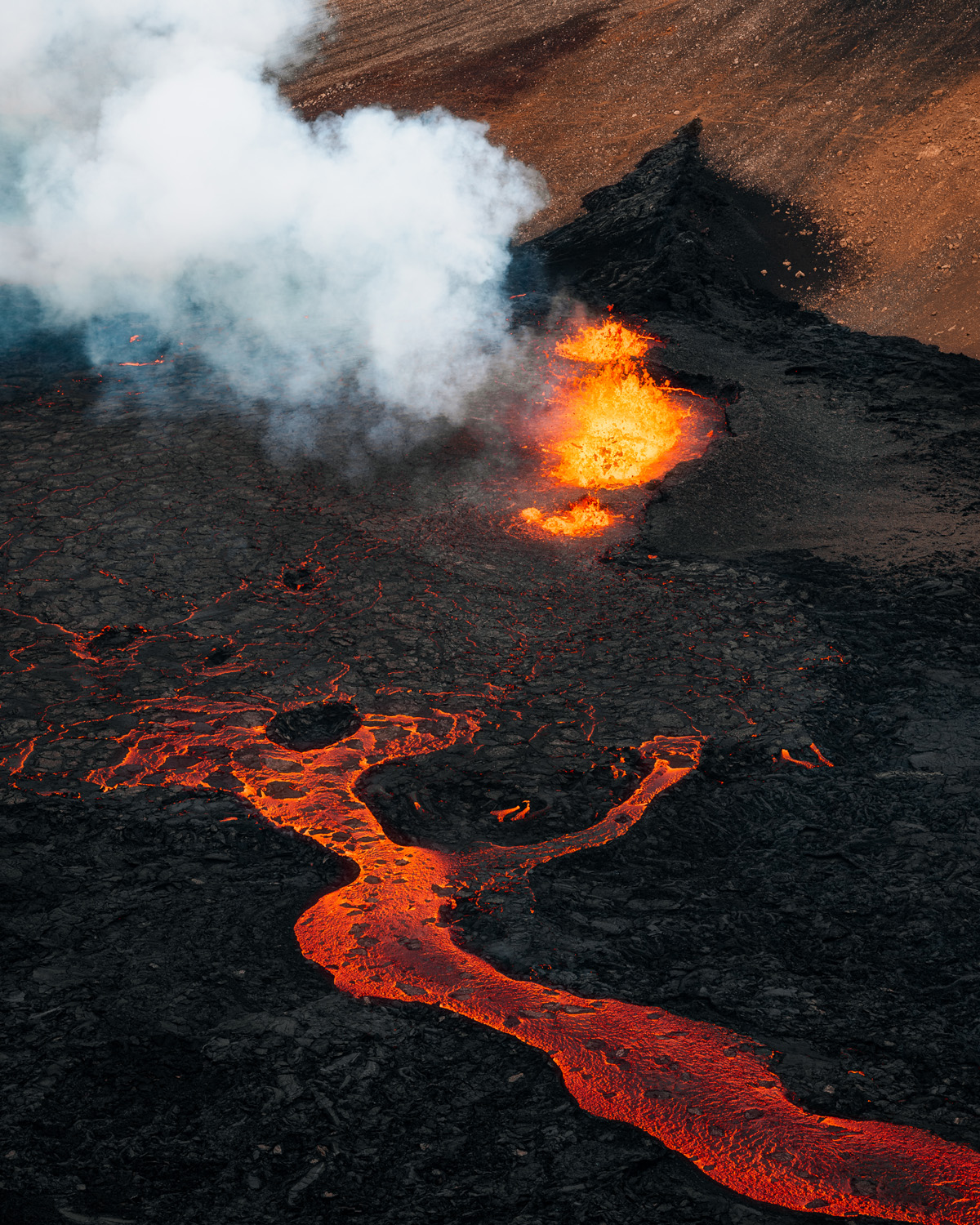 image of orange glowing lava flow oozing from volcano