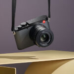 Product photo of Leica Q3 43 hanging by its strap above a modern table against a great background